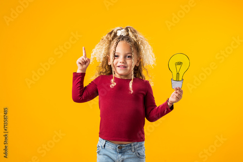 Фотография Idea Illumination. Child girl Genius with Paper Bulb.
