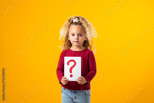 Enchanting Exploration. A Portrait of a Thoughtful child Girl Holding Cards with Question Marks and Exclamation Points.