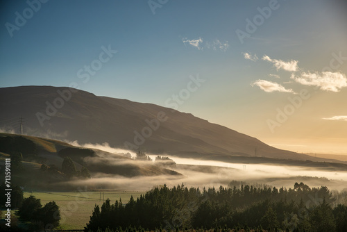 The Rural Hills of Berwick (south west of Dunedin) at sunrise on a freezing frosty day with low mist and fog rolling through the valleys