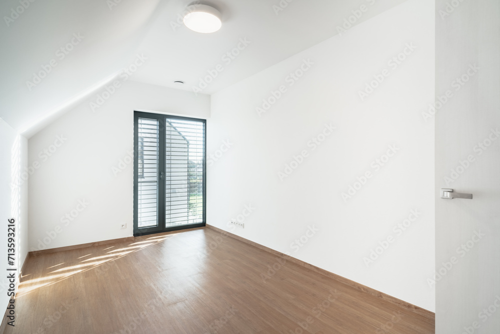 An empty attic room with a wooden floor and a glass window. The room is clean and tidy, and it looks like it could be used for a variety of purposes. An empty attic room with a wooden floor and a glass window. The room is clean and tidy, and it looks like it could be used for a variety of purposes.