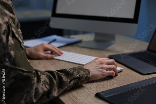 Military service. Soldier working at wooden table indoors, closeup
