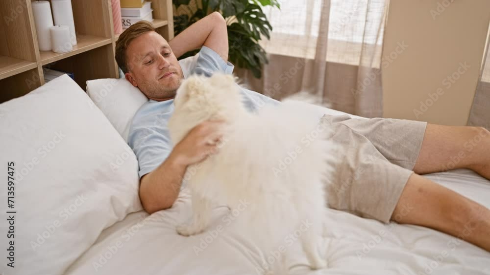 Young caucasian man with dog smiling confident lying on bed playing at bedroom Young caucasian man with dog smiling confident lying on bed playing at bedroom