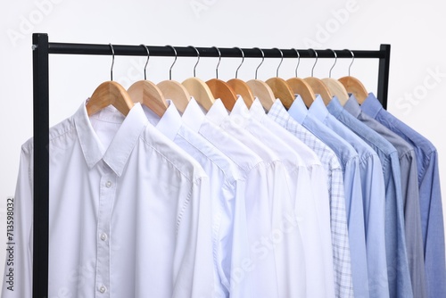 Dry-cleaning service. Many different clothes hanging on rack against white background, closeup