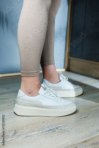 White leather women's classic sneakers on the feet. Stylish women's shoes for the summer. Collection of summer women's shoes.