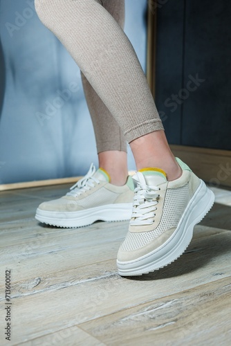 Close-up of female legs in leather sneakers on feet. Modern seasonal collection of stylish sneakers. Women's fashion.