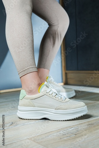 Close-up of female legs in leather sneakers on feet. Modern seasonal collection of stylish sneakers. Women's fashion.