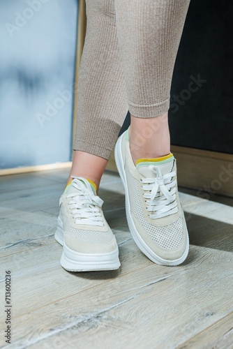 Close-up of female legs in leather sneakers on feet. Modern seasonal collection of stylish sneakers. Women's fashion.