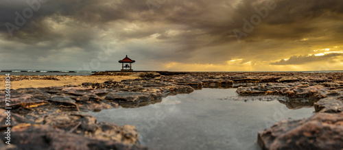 Slika na platnu A picturesque gazebo temple stands atop the rocky beach, framed by billowing clo