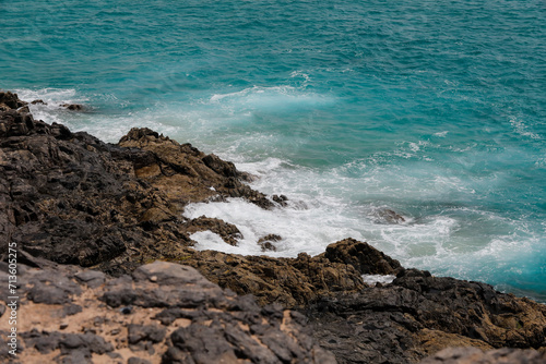 Ozean türkis mit hellen weißen Schaumkronen spült an eine Steilklippe