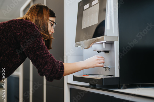 Stunning woman taking her coffee from the coffee maker.