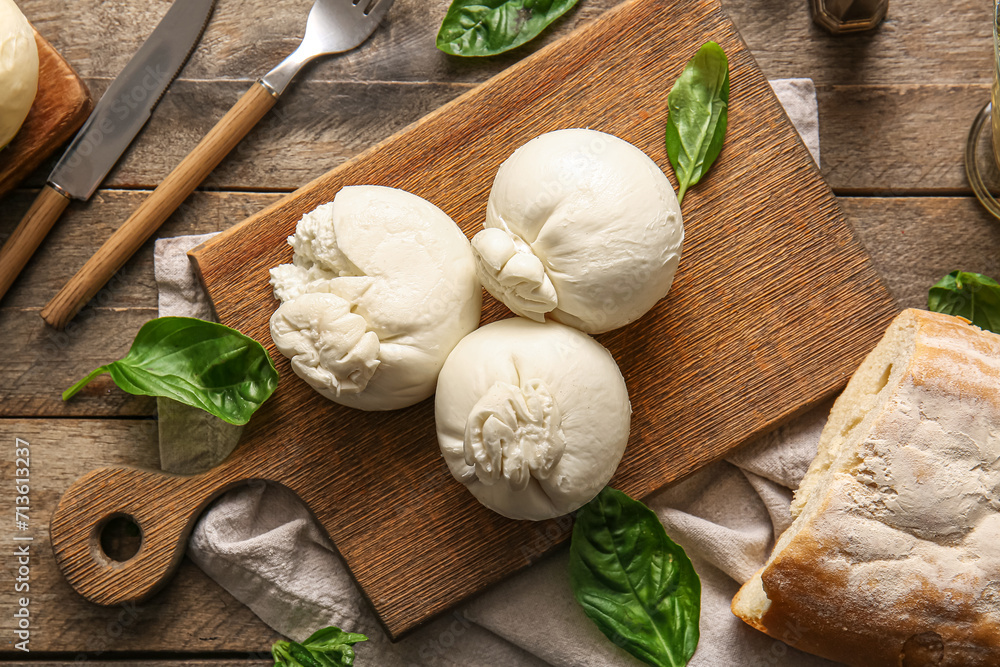 Board of tasty Burrata cheese with basil on wooden background