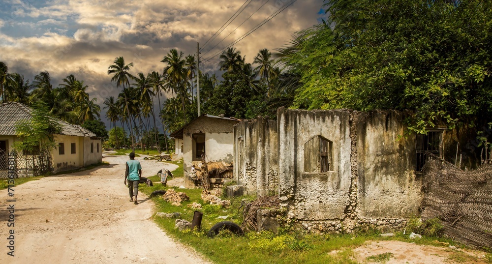 a local resident walking in a residential area just off the white sand beach at Jambaiani, Zanzibar