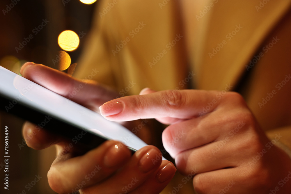 Woman using smartphone on blurred background, closeup