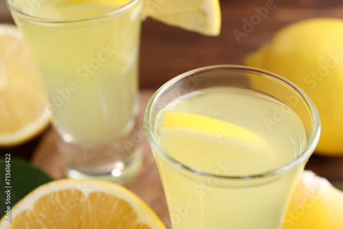 Tasty limoncello liqueur with lemon on table, closeup. Space for text