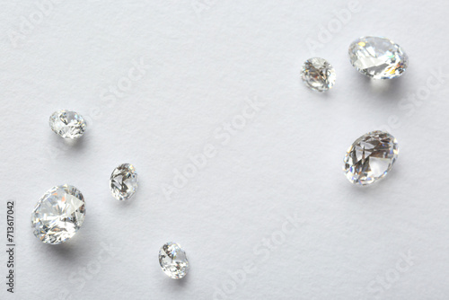 Many beautiful shiny diamonds on white background, flat lay. Space for text