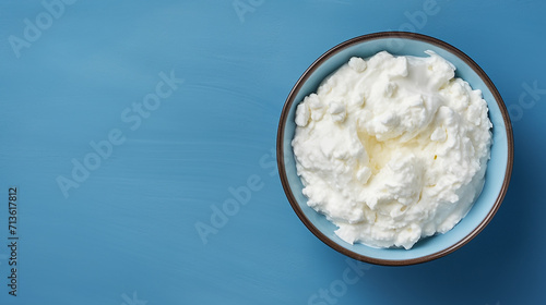 Cottage cheese in a bowl on a blue background, top view	