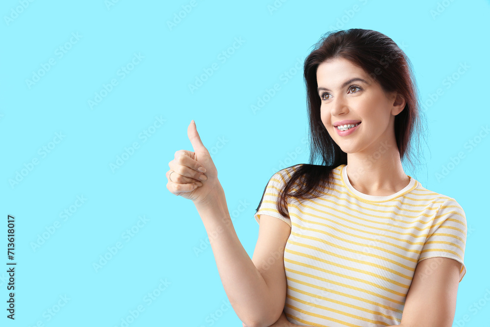 Young woman with dental braces showing thumb-up on blue background Young woman with dental braces showing thumb-up on blue background