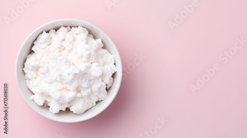Cottage cheese in white bowl on pink background with copy space.