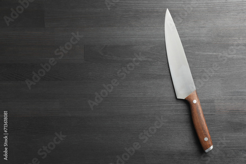 One sharp knife on black wooden table, top view. Space for text