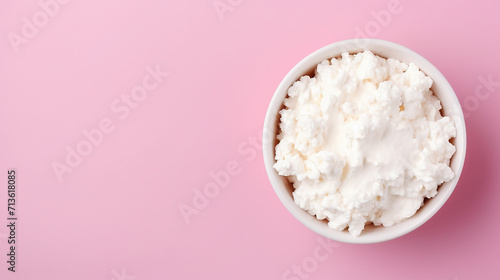 Cottage cheese in white bowl on pink background with copy space.