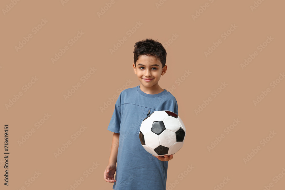 Cute little boy with soccer ball on beige background Cute little boy with soccer ball on beige background