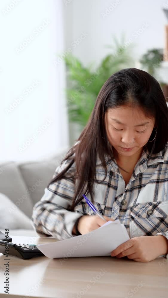 Chinese woman using calculator at home. Person calculating expenses. Chinese woman using calculator at home. Person calculating expenses.