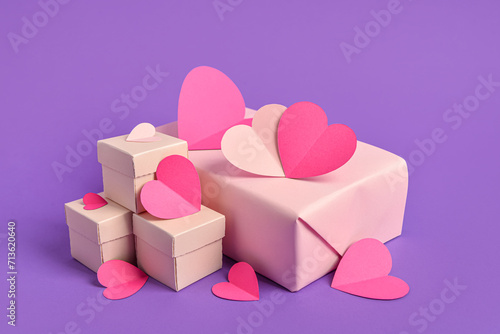 Paper hearts with gift boxes on purple background