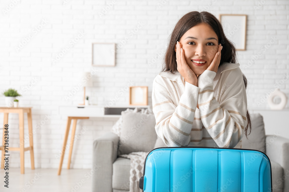 Happy young woman with suitcase at home Happy young woman with suitcase at home