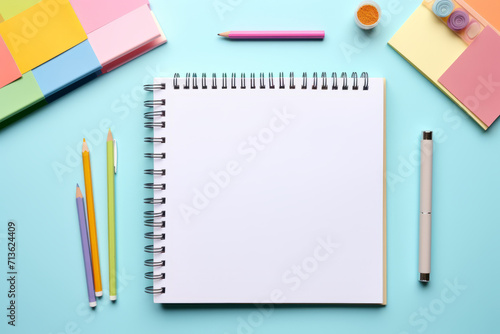 Business stationery on blue trending background. Notepad, colorful stickers, pens, pencils. Top view, flat lay. Mockup, copy space.