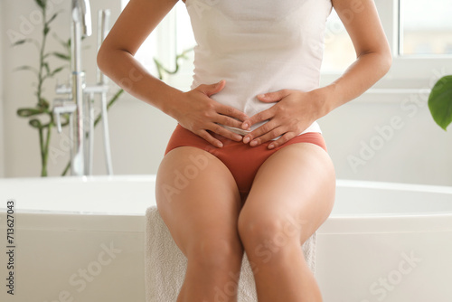 Young woman wearing red menstrual panties in bathroom, closeup