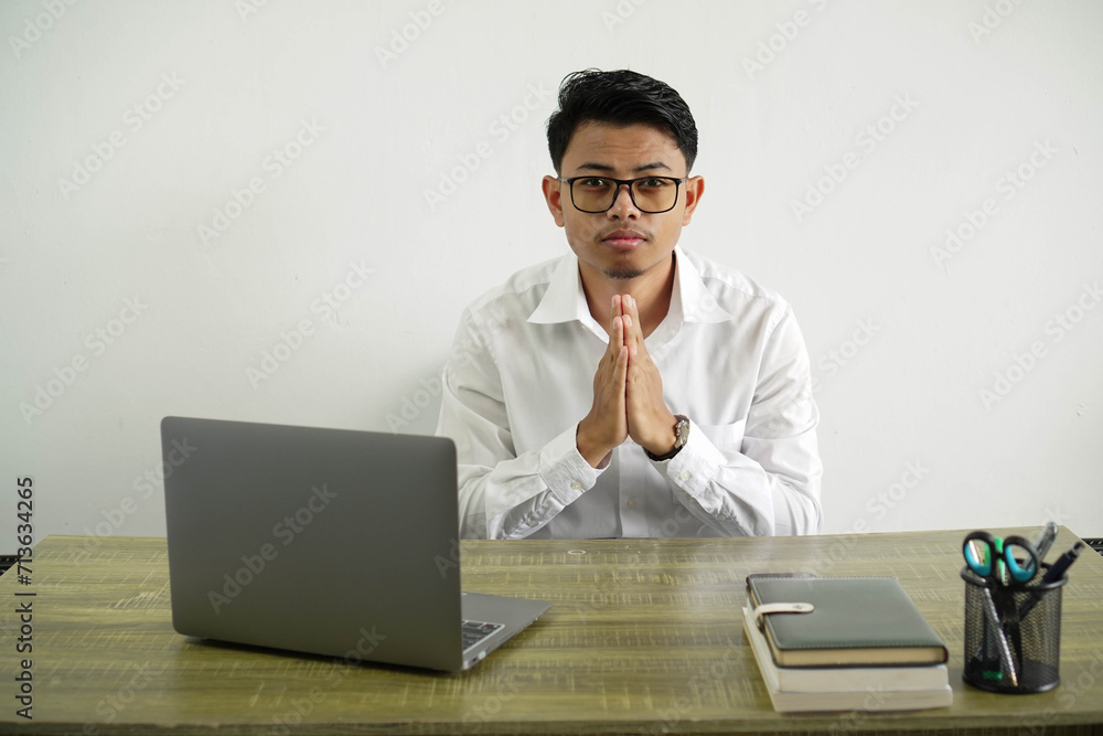young asian businessman in a workplace keeps palm together. person asks for something, wear white shirt with glasses isolated young asian businessman in a workplace keeps palm together. person asks for something, wear white shirt with glasses isolated