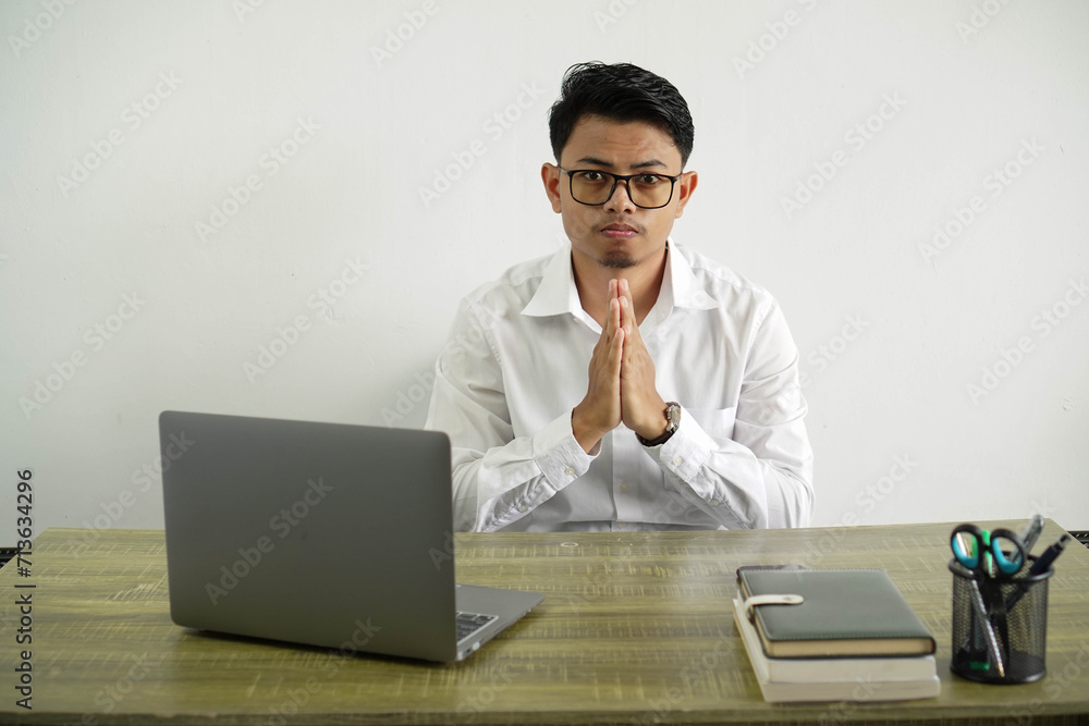 young asian businessman in a workplace keeps palm together. person asks for something, wear white shirt with glasses isolated young asian businessman in a workplace keeps palm together. person asks for something, wear white shirt with glasses isolated