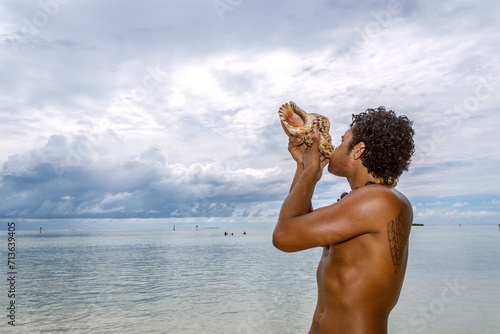 Local tahitian man blowing a conch shell, Moorea, French Polynesia