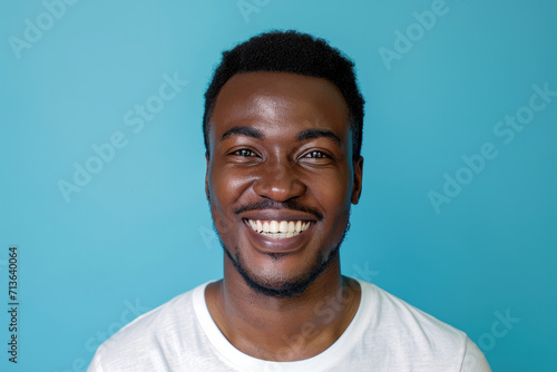 A man in a white shirt is smiling with a blue background