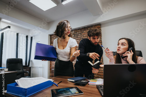Tablou pe pânză Busy office scene with stressed colleagues discussing work, multitasking woman on phone, hectic teamwork environment