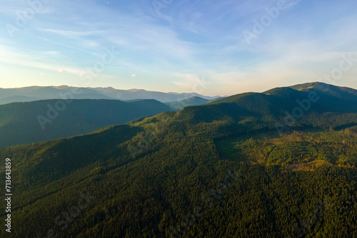Aerial view of amazing scenery with dark mountain hills covered with forest pine trees at autumn sunrise. Beautiful wild woodland at dawn © bilanol
