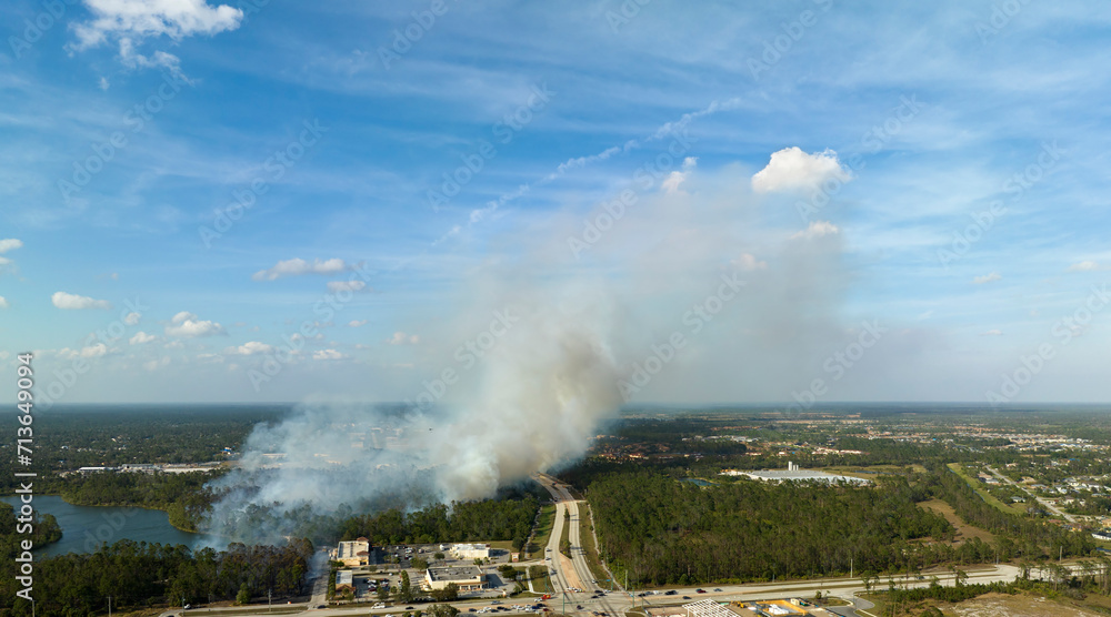 View from above of lagre wildfire burning severely in North Port city, Florida. Hot flames in forest with toxic smoke polluting atmosphere