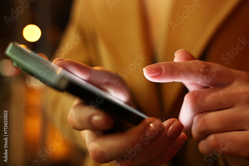 Woman using smartphone on blurred background, closeup © New Africa