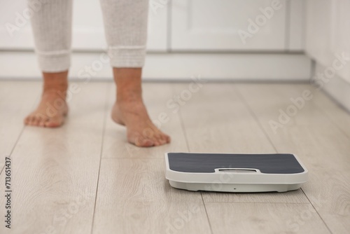 Menopause, weight gain. Woman standing on floor indoors, focus on scales photo