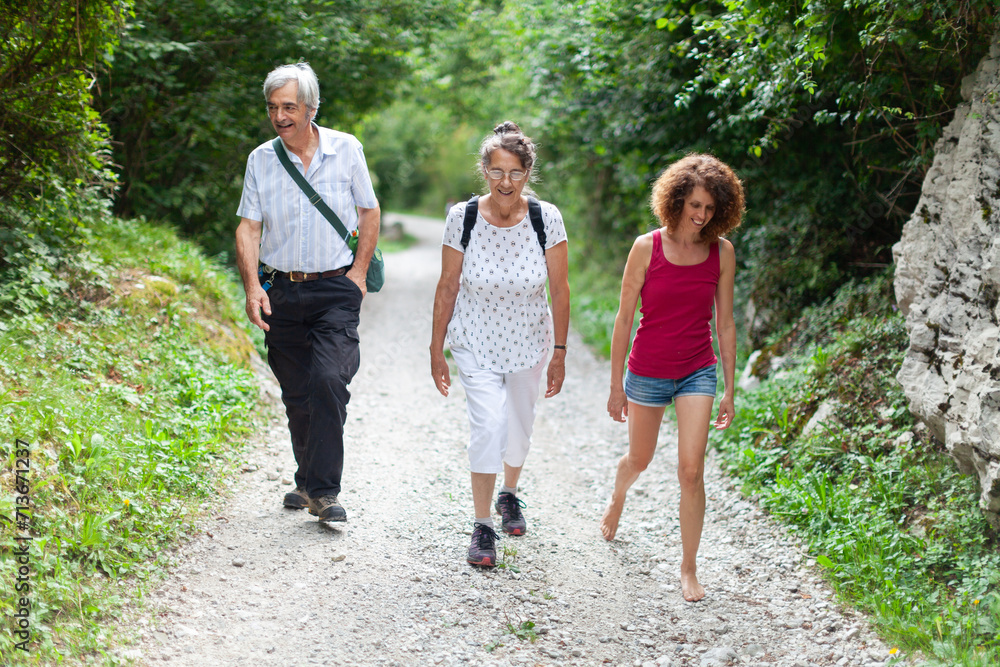 Fototapeta premium Senior Couple and their Mature Adult Daughter Having a Walk on Fresh Air Outdoors in Nature
