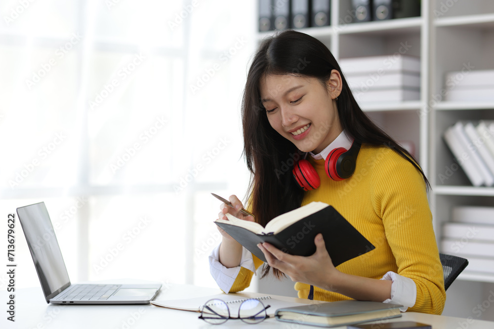 Beautiful Asian female student reading academic books in university library. Beautiful Asian female student reading academic books in university library.