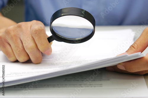 Focus magnifying glass, Hand of businessperson looking at documents through magnifying glass. Concept of business and data validation.