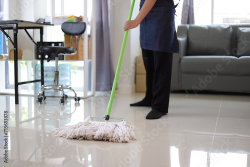 Cleaner is mopping floors at home with a mop.