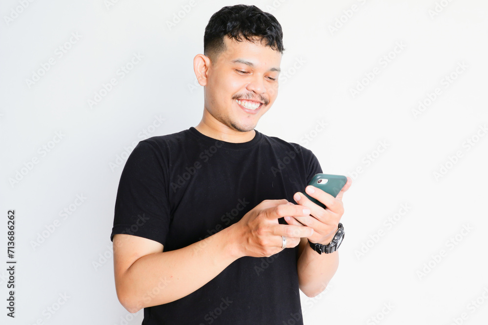 an asian man showing happy expression holding his smartphone an asian man showing happy expression holding his smartphone