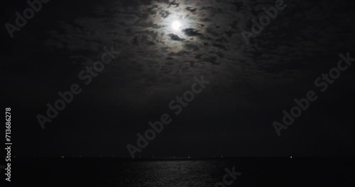 雲の後ろに月が浮かぶ海の風景。 photo