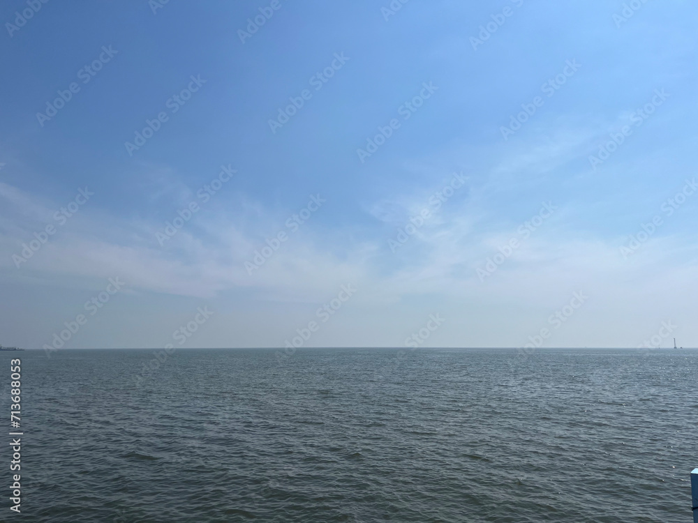 A photograph of a horizon with a blue sky and a dark sea.