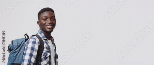 Positive african american millennia guy student in casual posing on grey studio background, young black man enjoying studying at university or college, copy space. Young man traveling with backpack photo