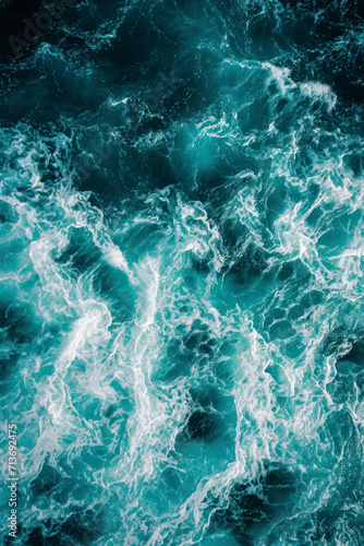 Vertical  aerial view from above of turquoise ocean water with splashes and foam for abstract natural background and texture. © Hunman