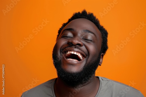 Close up of man's carefree laughter, orange studio environment © Lucija