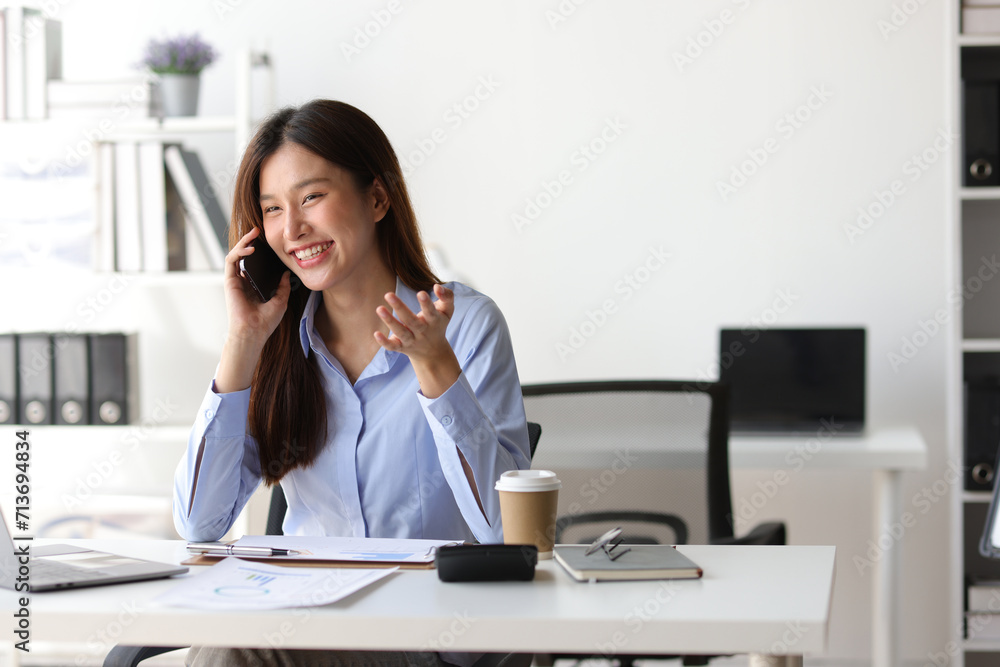 Asian woman in office is using mobile phone and calling someone, she is smiling with joy and surprise when receiving good news. Asian woman in office is using mobile phone and calling someone, she is smiling with joy and surprise when receiving good news.